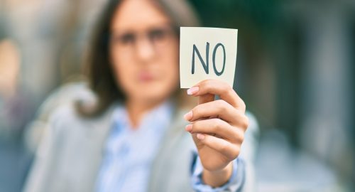 Young hispanic businesswoman with serious expression holding reminder with no message at the city.